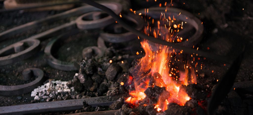 Ironworker forging hot iron in workshop